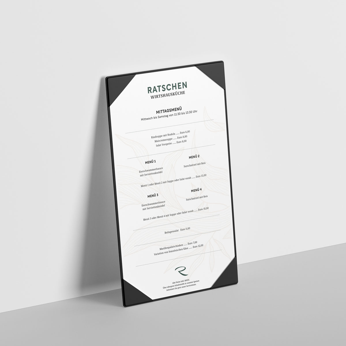 Eine aufrecht stehende Menükarte der Ratschen-Wirtshausküche lehnt an einer hellen Wand. Die Karte ist weiß, schlicht gestaltet und zeigt das Mittagsmenü.